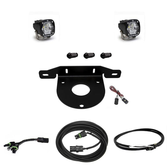 The Baja Designs 2021+ Ford Bronco Dual S1 W/C Reverse Kit w/Upfitter includes two LED off-road lights by Baja Designs, a black metal mounting bracket, three small cylindrical mounts, various wiring harnesses, connectors, and fasteners—all neatly arranged against a white background. This kit is ideal for enhancing the illumination of your Ford Bronco.