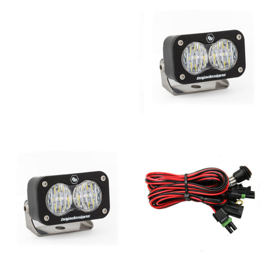 The Baja Designs S2 Sport Wide Cornering Pattern Pair LED Work Light - Clear is shown with metal mounting brackets and a bundle of red and black wiring with connectors, designed for enhanced visibility on rugged terrains.