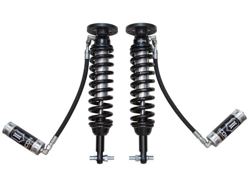 The ICON 2015 Ford F-150 4WD 2-2.63in 2.5 Series Shocks VS RR Coilover Kit includes two automotive shock absorbers with coil springs and attached reservoirs. These black shocks feature metallic components and are connected by tubes to small cylindrical reservoirs labeled "ICON," making them perfect for Ford F150 coilover shocks enthusiasts looking to enhance their vehicle's performance.