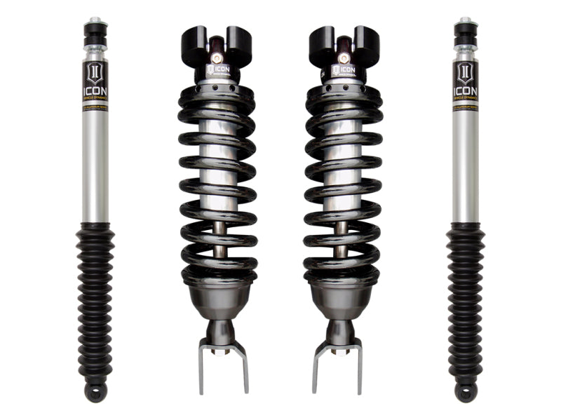 Four automotive shock absorbers and coilover springs from ICON. The two coilover shocks with black springs are in the center, flanked by the shock absorbers on the sides. All components feature a metallic finish with black and minor yellow accents, designed to enhance vehicle control for your Dodge Ram 1500 suspension. This is part of the ICON 2019+ Ram 1500 2/4WD .75-2.5in Stage 1 Suspension System from ICON Vehicle Dynamics.